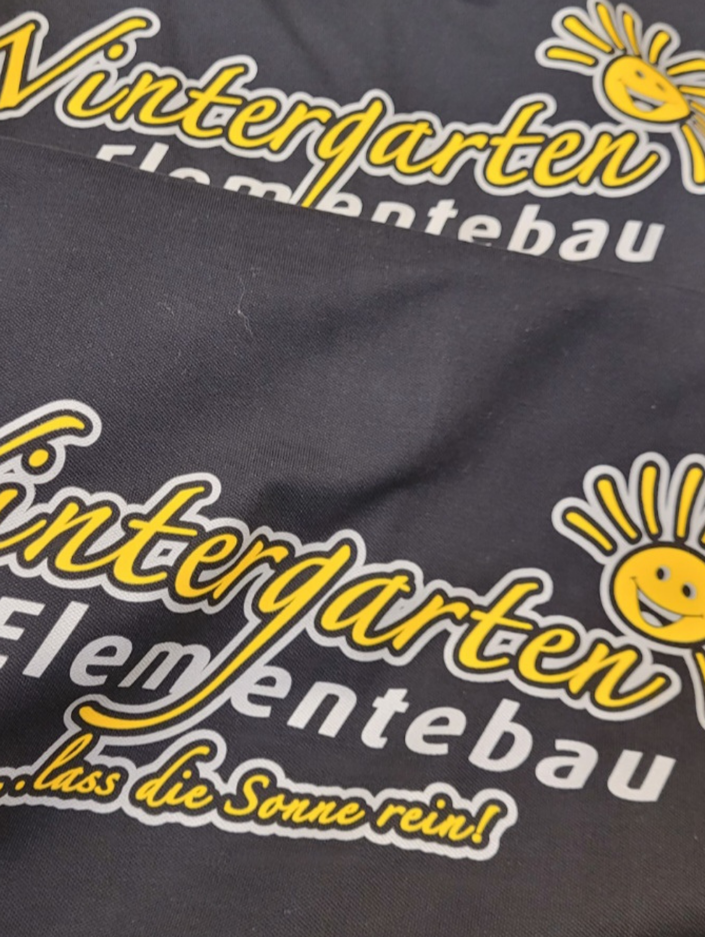 Dunkle Shirts mit gelbem Wintergarten-Elementebau-Logo