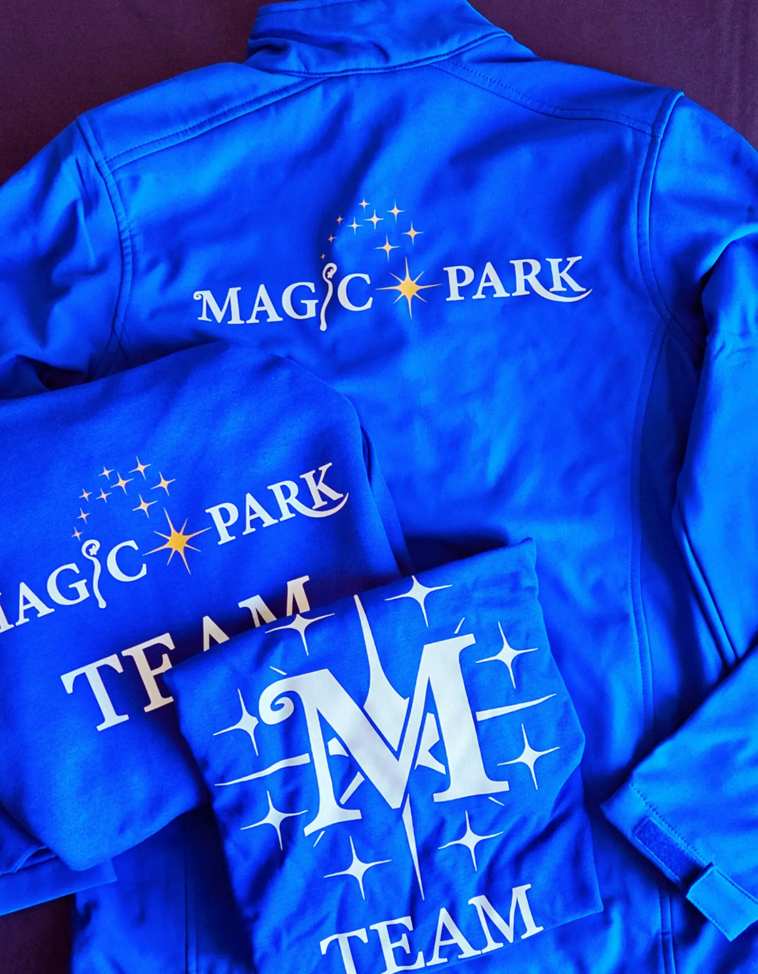 Blaue Softshelljacken und Hoodies mit Magic-Park-Teamdruck