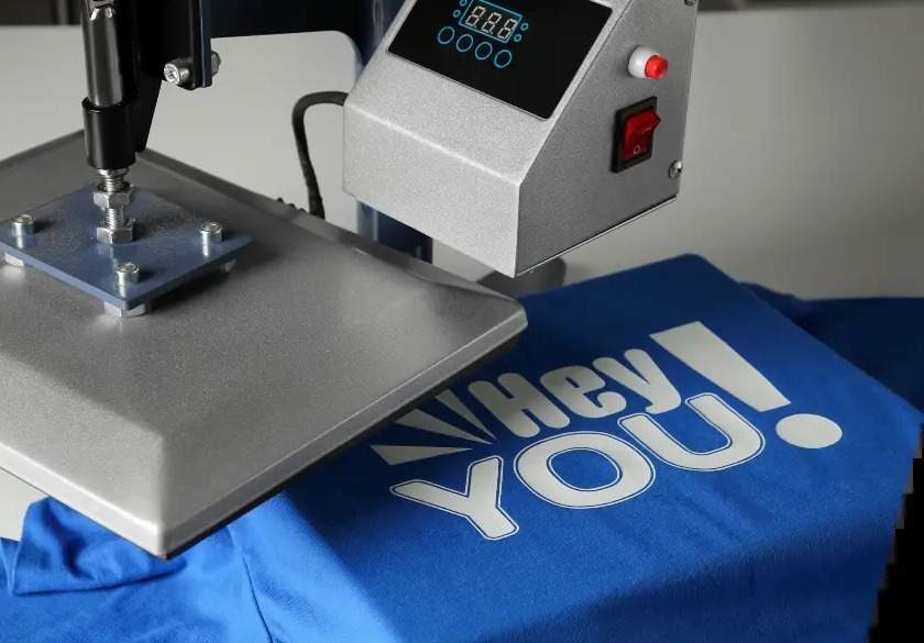 Transferpresse presst ein Motiv auf ein blaues T-Shirt